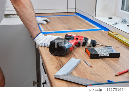 repairman working on a new kitchen installation and using electric drill 132751664