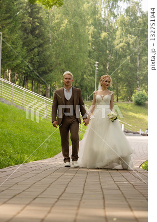 Newlyweds stroll hand in hand on a sunny day in a park Newlyweds stroll hand in hand on a sunny day in a park 132751944