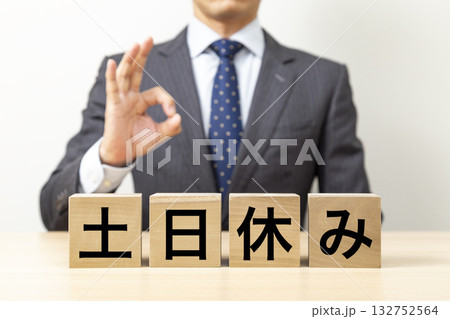「土日休み」と書かれたブロックとOKポーズをするビジネスマン 132752564