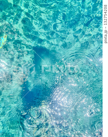Close-up of the water of a swimming pool with the sunlight reflection. The scene of the swimming pool in the sunny day. Relaxation and holiday concept. Close-up of the water of a swimming pool with the sunlight reflection. The scene of the swimming pool in the sunny day. Relaxation and holiday concept. 132754208