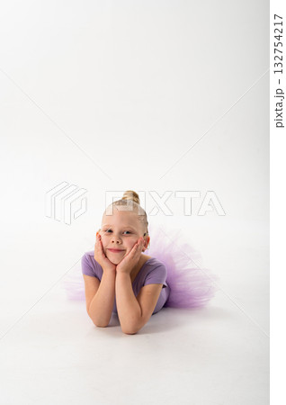 Little ballerina with cochlear implant lying on floor and smiling. Childhood inclusion, relaxation, and hearing awareness through art, grace, and joy. 132754217