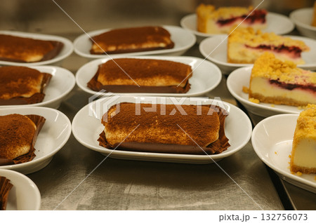 Assorted tiramisu and cheesecake slices on plates in a bakery setting 132756073