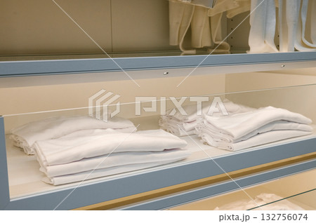 Organized closet shelf with neatly folded white shirts and towels Organized closet shelf with neatly folded white shirts and towels 132756074