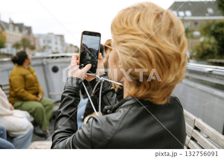 Young caucasian female capturing scenic boat ride moment with smartphone Young caucasian female capturing scenic boat ride moment with smartphone 132756091
