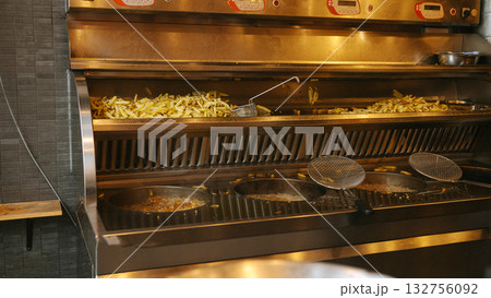 Commercial kitchen fryer with freshly cooked french fries and frying baskets 132756092