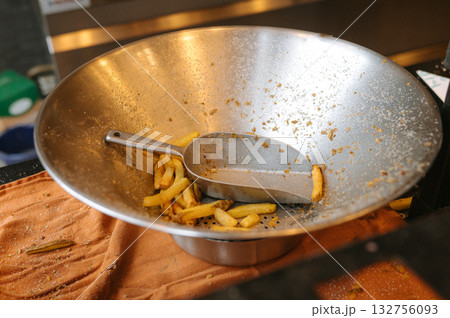 Stainless steel bowl with french fries and metal scoop in kitchen setting 132756093