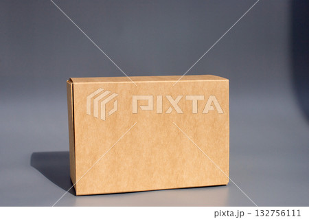 Plain brown cardboard box on gray background with shadow Plain brown cardboard box on gray background with shadow 132756111