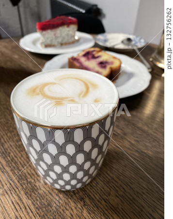 Coffee cup with latte art and slices of cake on a wooden table background 132756262