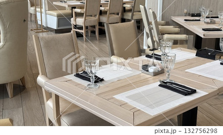 Restaurant dining area with elegant table settings and neutral-colored chairs for classy meals 132756298