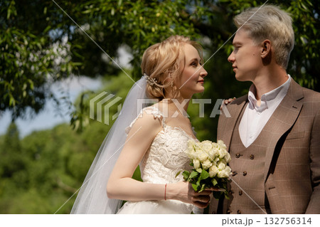 Couple exchanges loving glances in lush outdoor setting during wedding ceremony Couple exchanges loving glances in lush outdoor setting during wedding ceremony 132756314