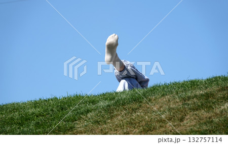 Legs clad in socks, one leg on top of the other, human resting pose on a hill 132757114