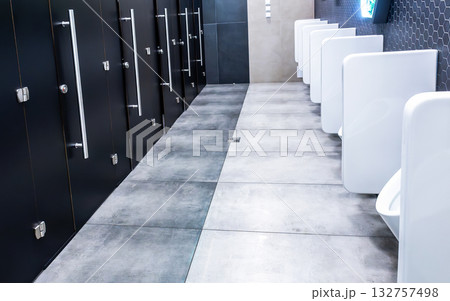 Interior of public bathroom with cabins and ceramic urinals Interior of public bathroom with cabins and ceramic urinals 132757498