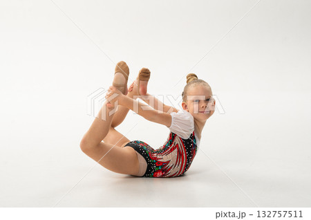 Smiling gymnast with cochlear implant performing flexibility pose. Celebration of inclusion, sound recovery, and motivation through rhythmic gymnastics. 132757511