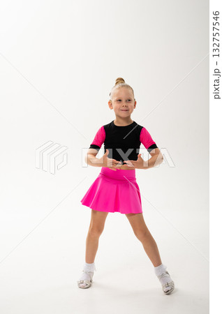 Smiling girl in pink dance outfit with cochlear implant performing studio pose. Celebration of hearing restoration, inclusion, and artistic confidence in children dance and movement. Smiling girl in pink dance outfit with cochlear implant performing studio pose. Celebration of hearing restoration, inclusion, and artistic confidence in children dance and movement. 132757546