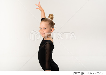 Smiling child in black ballroom outfit practicing elegant movement with hearing technology cochlear implant. Copy space. Strength, inclusion, and artistic discipline harmonize to celebrate diversity 132757552