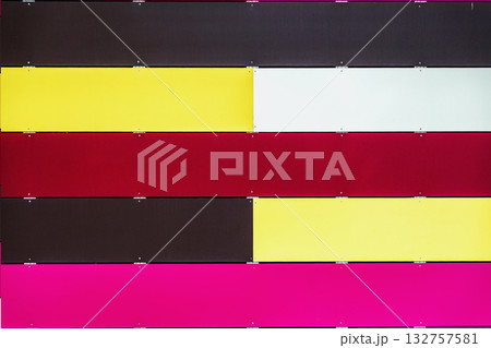 Striped wall with alternating colorful horizontal metal panels in red, yellow, pink, white, black tones. Modern design, urban decorative color palette Striped wall with alternating colorful horizontal metal panels in red, yellow, pink, white, black tones. Modern design, urban decorative color palette 132757581