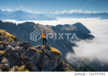 Woman with backpack on mountain ridge above a sea of clouds 132757591