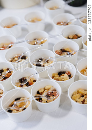 Paper cups with assorted dried fruits and nuts served with plastic spoons on event table 132757706