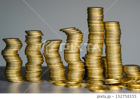 Leaning stacks of gold coins symbolizing financial instability, economic imbalance, and risk Leaning stacks of gold coins symbolizing financial instability, economic imbalance, and risk 132758155