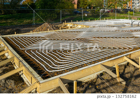 Underfloor heating installation with plastic pipes in concrete foundation at new house construction site Underfloor heating installation with plastic pipes in concrete foundation at new house construction site 132758162