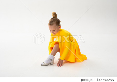 Little dancer with cochlear implant adjusting shoe on white floor. Copy space. Inclusion, discipline, and awareness of hearing technology in early childhood art. Little dancer with cochlear implant adjusting shoe on white floor. Copy space. Inclusion, discipline, and awareness of hearing technology in early childhood art. 132758255