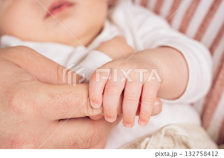 Close-up of baby hand holding parents finger. Symbol of love, trust, and protection in soft natural light perfect for family, care, or newborn themes Close-up of baby hand holding parents finger. Symbol of love, trust, and protection in soft natural light perfect for family, care, or newborn themes 132758412