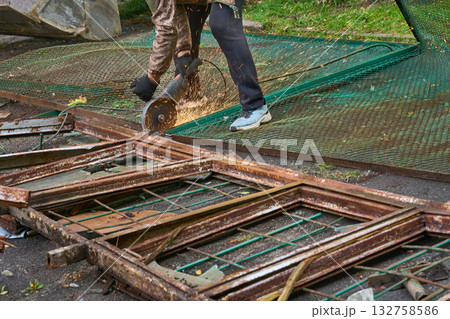 A worker cuts metal construction waste with a chop saw A worker cuts metal construction waste with a chop saw 132758586
