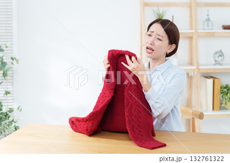 衣替えで出したセーターに問題を見つけた女性 132761322