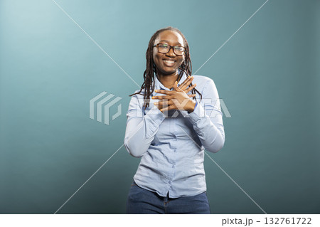 Cheerful black female model celebrates with confident dance, expressing excitement and good vibes in studio. African American woman in blue shirt dancing with energy, radiating positivity. 132761722