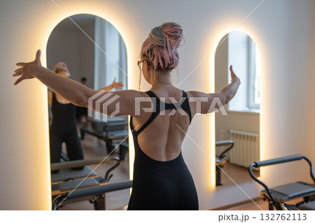 Woman with dreadlocks determined woman in black leggings performs pilates with focused energy Woman with dreadlocks determined woman in black leggings performs pilates with focused energy 132762113