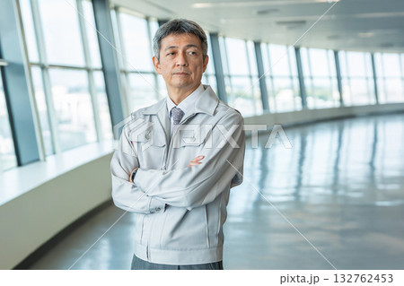 オフィスの廊下に立つ作業服を着たシニア男性 132762453