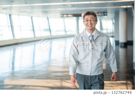 オフィスの廊下に立つ作業服の男性 132762749