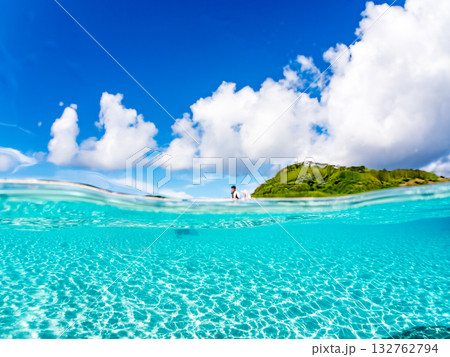 白砂のビーチの半水面撮影。美しいサンゴ礁と熱帯魚の群れ。 嘉比島沖縄県 島尻郡慶良間諸島座間味島 132762794