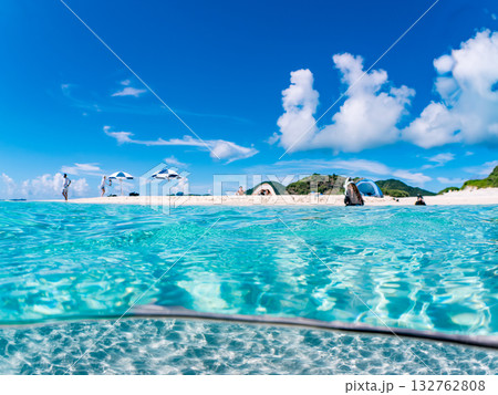 白砂のビーチの半水面撮影。美しいサンゴ礁と熱帯魚の群れ。 嘉比島沖縄県 島尻郡慶良間諸島座間味島 132762808