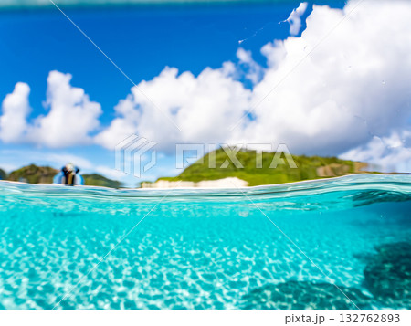 白砂のビーチの半水面撮影。美しいサンゴ礁と熱帯魚の群れ。 嘉比島沖縄県 島尻郡慶良間諸島座間味島 132762893