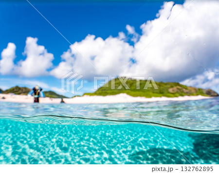 白砂のビーチの半水面撮影。美しいサンゴ礁と熱帯魚の群れ。 嘉比島沖縄県 島尻郡慶良間諸島座間味島 132762895