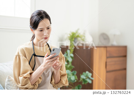 スマホを見ながら悩む女性 スマホを見ながら悩む女性 132763224