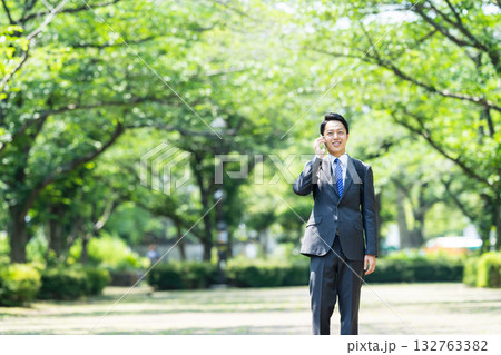 公園で電話をするビジネスマン 公園で電話をするビジネスマン 132763382