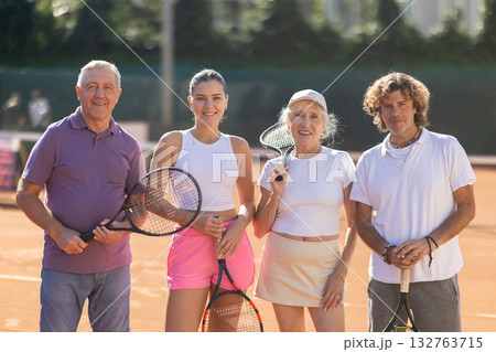 Group of friends or family in sportswear spending time playing sports and posing on tennis courts after match Group of friends or family in sportswear spending time playing sports and posing on tennis courts after match 132763715