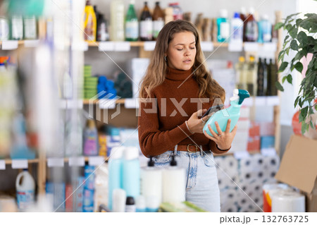 Young woman scanning QR-code on cleaning spray in supermarket 132763725