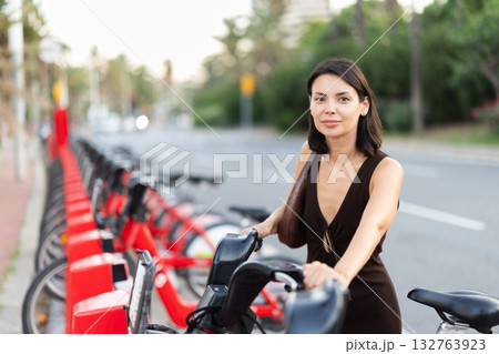 Young girl taking red bicycle from Bicing rental station 132763923