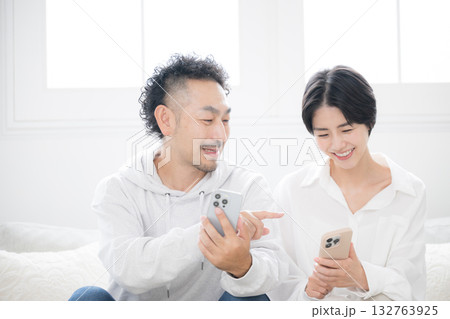 リビングでスマホを一緒に見るミドルの笑顔の夫婦やカップル 132763925