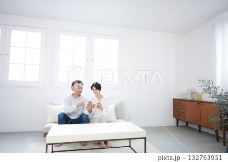 リビングでスマホを見るミドルの笑顔の夫婦やカップル 132763931