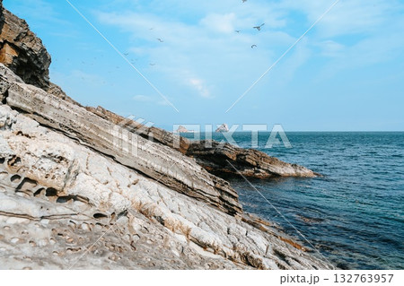 Rocky coastal landscape at Desantnaya Bay in Vladivostok, Russia, overlooking the blue waters of the Japanese Sea under a clear winter sky. 132763957