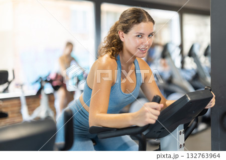Woman exercising on an exercise bike in the gym Woman exercising on an exercise bike in the gym 132763964