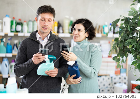 Couple man and woman scanning qr code for cleaning spray Couple man and woman scanning qr code for cleaning spray 132764003