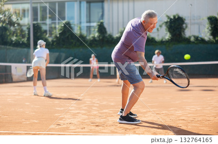 Elderly couple playing tennis together on summer court Elderly couple playing tennis together on summer court 132764165