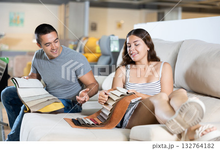 Husband and wife choose color and material for future sofa according to the samples of materials in furniture store 132764182