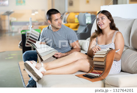 Smiling woman and man choosing upholstery for sofa in furnishing store Smiling woman and man choosing upholstery for sofa in furnishing store 132764201
