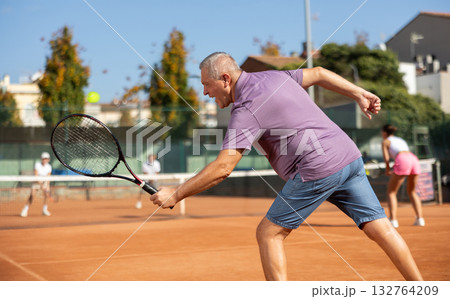 Elderly man playing tennis 132764209